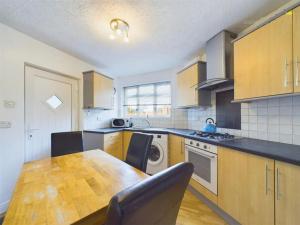 a kitchen with a wooden table and a kitchen with a washer at 1 Buttermere road in Lancaster