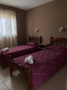 two beds in a room with purple sheets and towels at Alquiler temporario zapala Amanecer in Zapala