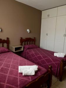 a bedroom with two beds with purple sheets and white towels at Alquiler temporario zapala Amanecer in Zapala