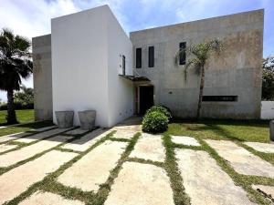 a white building with a palm tree in front of it at Villa Sérénité Cabo Negro in Bicas