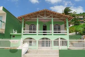 a green house with a white fence in front of it at O Recanto M&M na Praia de Fora. in Palhoça