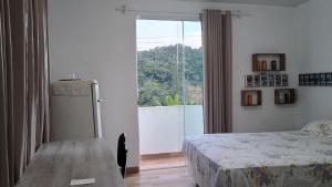a bedroom with a bed and a table and a window at Suíte itaporanga in Santa Maria Madalena