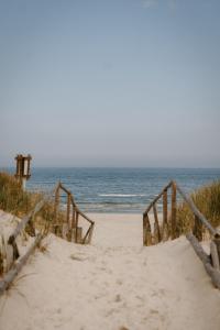 a beach with a wooden staircase leading to the ocean at Domki Ulkowo in Słajszewo