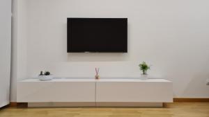 um armário branco com uma televisão numa parede branca em Piso Vega Foz em Foz