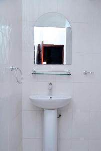 a white bathroom with a sink and a mirror at Welcoming abode in the heart of Osu - Apartment 3 in Accra