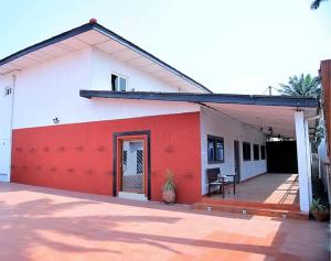 a white and red house with a red garage at Welcoming abode in the heart of Osu - Apartment 3 in Accra
