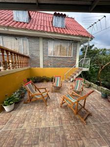 a patio with two chairs and a house at Finca Santa Lucia, Anolaima in Anolaima
