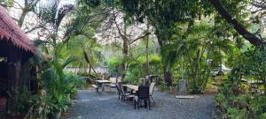 una mesa y sillas en un jardín con árboles en Congos Hostal y Camping en Playa Hermosa