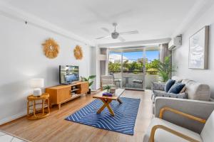 a living room with a couch and a tv at Beachfront 2-Bed with Pool, BBQ & Tennis Court in Gold Coast