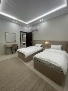 a bedroom with two beds and a desk in it at شقق فندقيه فاخره بتصمم عصري ودخول ذاتي in Jeddah