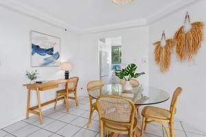 comedor con mesa de cristal y sillas en Beachfront 2-Bed with Pool, BBQ & Tennis Court, en Gold Coast