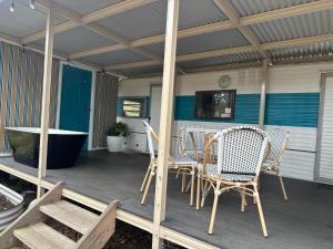 un portico con sedie, un tavolo e una vasca di Alice & Elvis, Crescent Head, Retro Caravans with Deck, Bathroom & Outdoor Bath in a Bush Setting near the Beach a Crescent Head