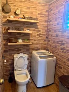 - une salle de bains avec toilettes dans une chambre dotée de murs en bois dans l'établissement Bliss Accommodation, à Malaybalay