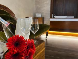 a table with two glasses and a vase with red flowers at Hotel Fiuggi Terme Resort & Spa in Fiuggi