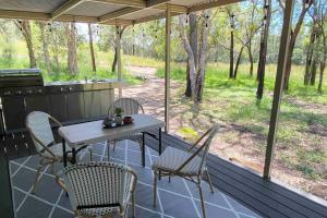 a patio with a table and chairs on a porch at Crescent Head, stylish retro caravan, deck, bathroom, private bush setting near beach in Crescent Head