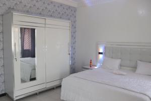 a white bedroom with a bed and a mirror at Bel appartement F2 Thies in Thiès