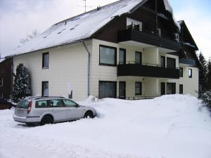 ein Auto, das auf einem Schneehaufen vor einem Haus parkt in der Unterkunft Wurmberg Baude 1 in Braunlage