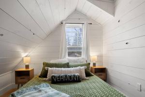 a bedroom with a bed and a window in a attic at 100% Renovated Stowe Village Farmhouse in Stowe