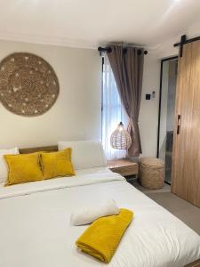 a bedroom with a white bed with yellow pillows at Spacious 2-Bedroom Mediterranean-Inspired Home in Ikeja