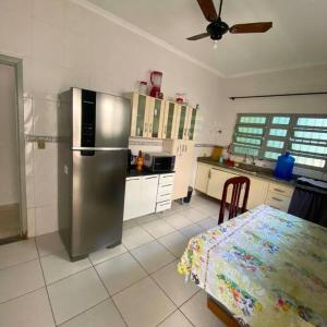 eine Küche mit einem Kühlschrank aus Edelstahl und einem Tisch in der Unterkunft Recanto Caiçara in Solemar