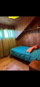 1 dormitorio con 1 cama azul en una habitación de madera en Casa a 4 cuadras del centro de Pucon en Pucón