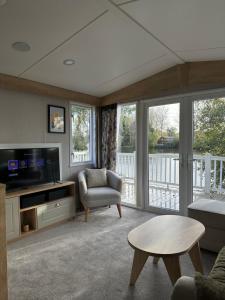 uma sala de estar com uma televisão, um sofá e uma mesa em Luxury Lakeside Lodge, Hot Tub & Private Fishing em Tattershall