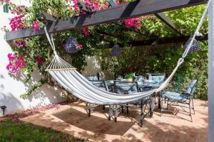 a hammock hanging under a pergola with tables and flowers at 3 bedroom villa, 10min walk to shops, bars & beach in Luz