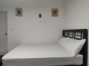 1 cama con sábanas blancas y 2 cuadros en la pared en Aparta Hotel Vista Verde#3, en Santa Bárbara de Samaná