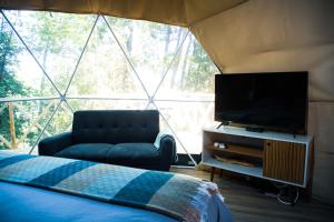 a bedroom with a bed and a tv in a tent at Domos Paseo Nativo in Chillán