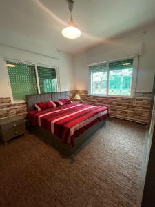 1 dormitorio con 1 cama grande en una habitación con ventanas en Andalius1, en Irbid