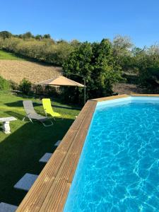 a pool with a wooden deck and two chairs and an umbrella at Appartement KELUTELO in Le Carbet