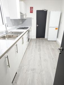 a kitchen with white cabinets and a wooden floor at Mile End Rooms in London