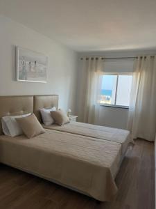 a bedroom with a large white bed with a window at Casa do Leme in Armação de Pêra