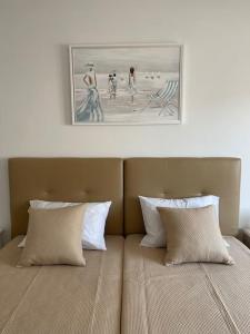 Una cama con dos almohadas y un cuadro encima. en Casa do Leme, en Armação de Pêra