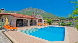 a swimming pool in a yard with chairs and a house at Villa Serena in Fethiye