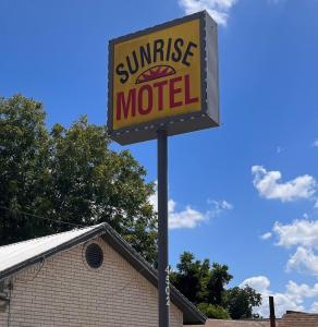 Sunrise Motel San Antonio في سان انطونيو: علامة لموتيل غروب الشمس أمام مبنى