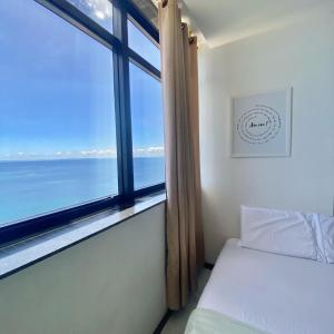 1 dormitorio con ventana y vistas al océano en Apartamento Vista Mar Salvador - Vista fantástica, en Salvador