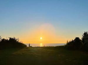 a sunset on the beach with the sun setting at Prime Beachfront - Sunsets, Space & Serenity in Hokitika
