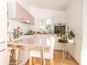 Una cocina con gabinetes blancos y una mesa y sillas. en Villa des Arts, en Draguignan