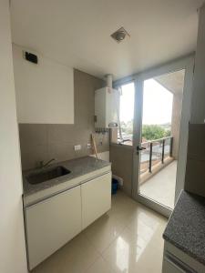 eine Küche mit einem Waschbecken und eine Tür zu einem Balkon in der Unterkunft Alquiler Temporario 3 Ambientes in Lincoln