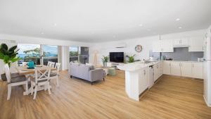 eine Küche und ein Wohnzimmer mit weißen Schränken und einem Tisch in der Unterkunft Nelson Bay CBD Apartment No 41 Nelson Towers in Nelson Bay