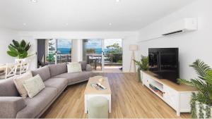a living room with a couch and a flat screen tv at Nelson Bay CBD Apartment No 41 Nelson Towers in Nelson Bay