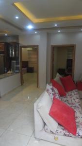 سما المزرعة في عمّان: غرفة معيشة مع أريكة بيضاء مع وسائد حمراء