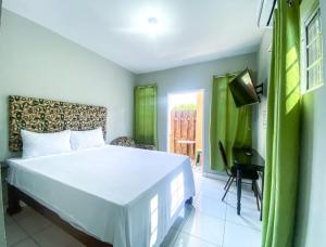 um quarto com uma cama branca e uma televisão em Jobs Inn Jamaica em Montego Bay