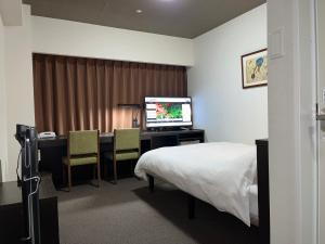 Schlafzimmer mit einem Bett und einem Schreibtisch mit einem TV in der Unterkunft Hotel Alpha-One Himeji Minamiguchi in Himeji