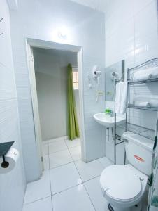a white bathroom with a toilet and a sink at Jobs Inn Jamaica in Montego Bay
