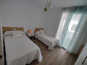 a white bedroom with two beds and a window at Apartamento El dragoncillo del Cabo in Las Negras