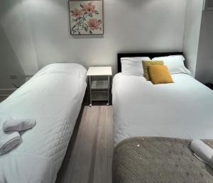 two twin beds in a room with a table at London Central Budget Rooms in London