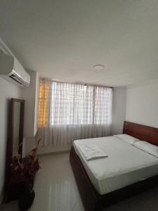 Un dormitorio con una cama grande y una ventana en Encantador apto en el Rodadero frente a la playa, en Santa Marta