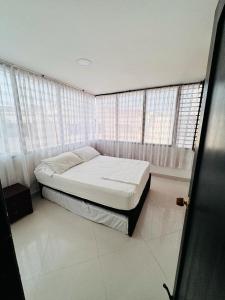 1 dormitorio con 1 cama en una habitación con ventanas en Encantador apto en el Rodadero frente a la playa, en Santa Marta